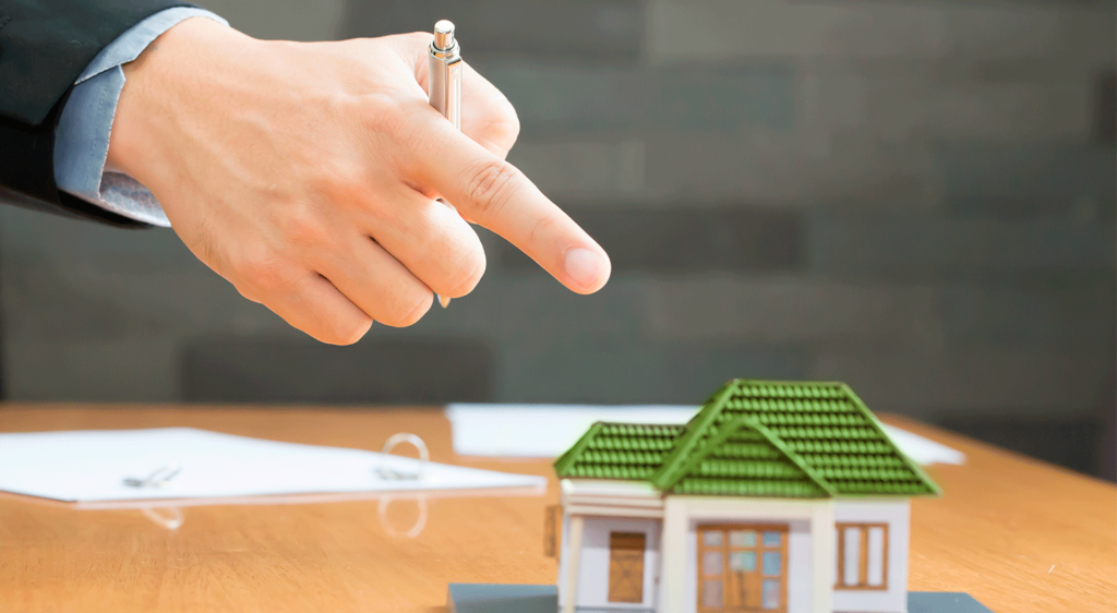 Dedo señalando una maqueta de una casa, simbolizando el embargo de bienes como medio para cobrar deudas