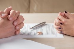 Pareja revisando un acuerdo de divorcio con un anillo sobre el documento relacionado con la pensión compensatoria